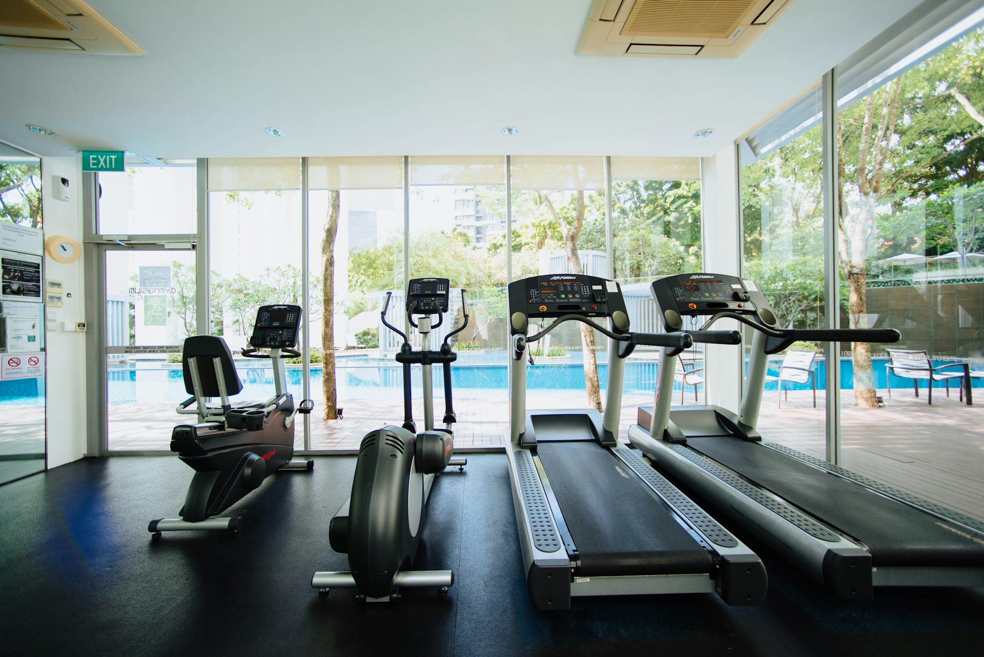 A treadmill and stationary bikes catch soft light in an empty room.